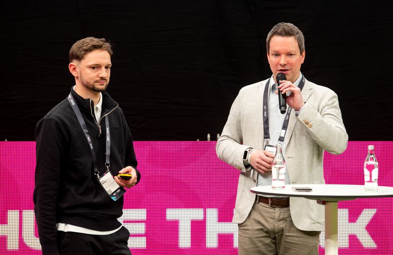 The picture shows our CEO Ulf Loetschert and Merlin Klüver from 1. FC Köln standing together on stage at SPOBIS 2026 in front of a bright pink video wall.
