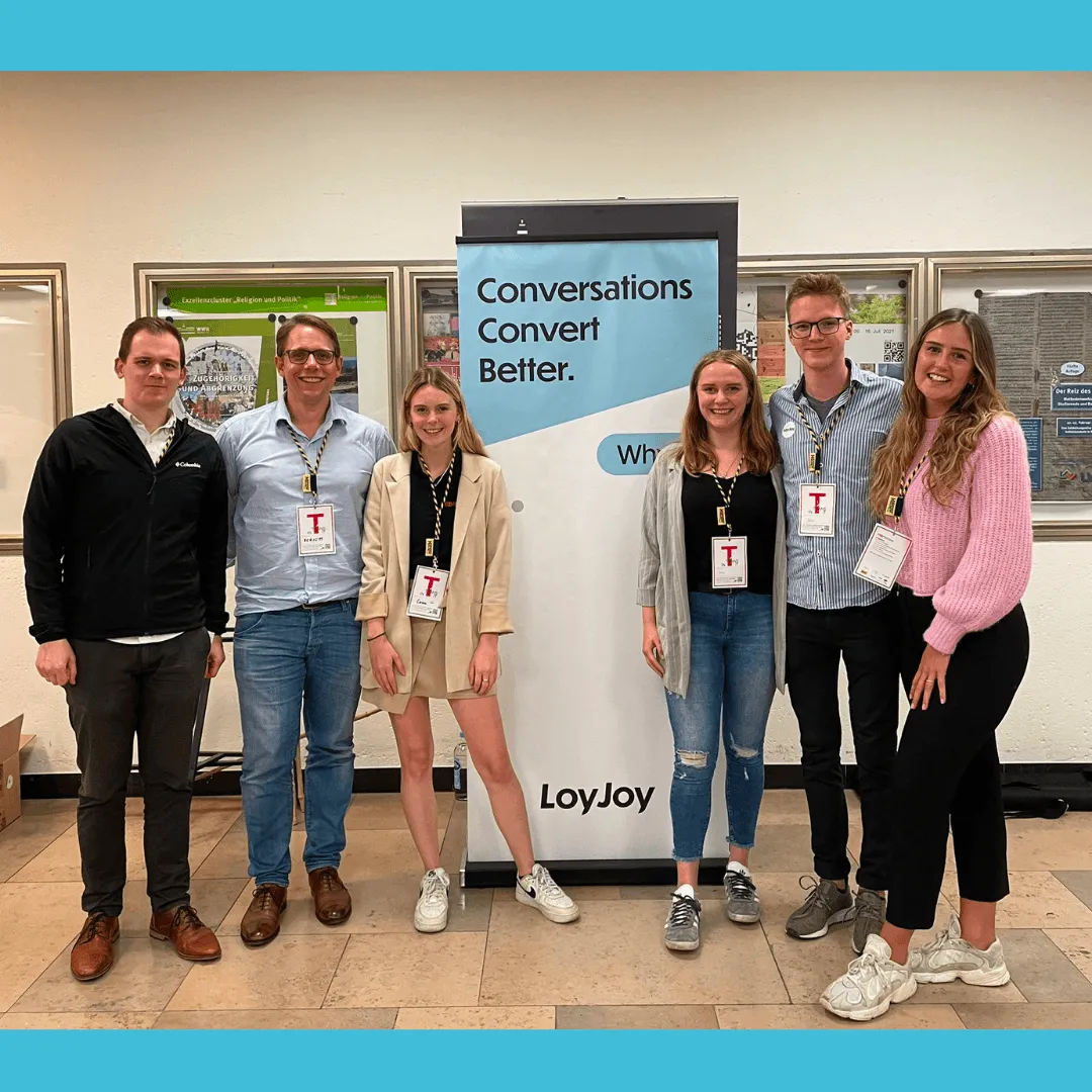 Das LoyJoy-Team steht vor einem LoyJoy-Display.