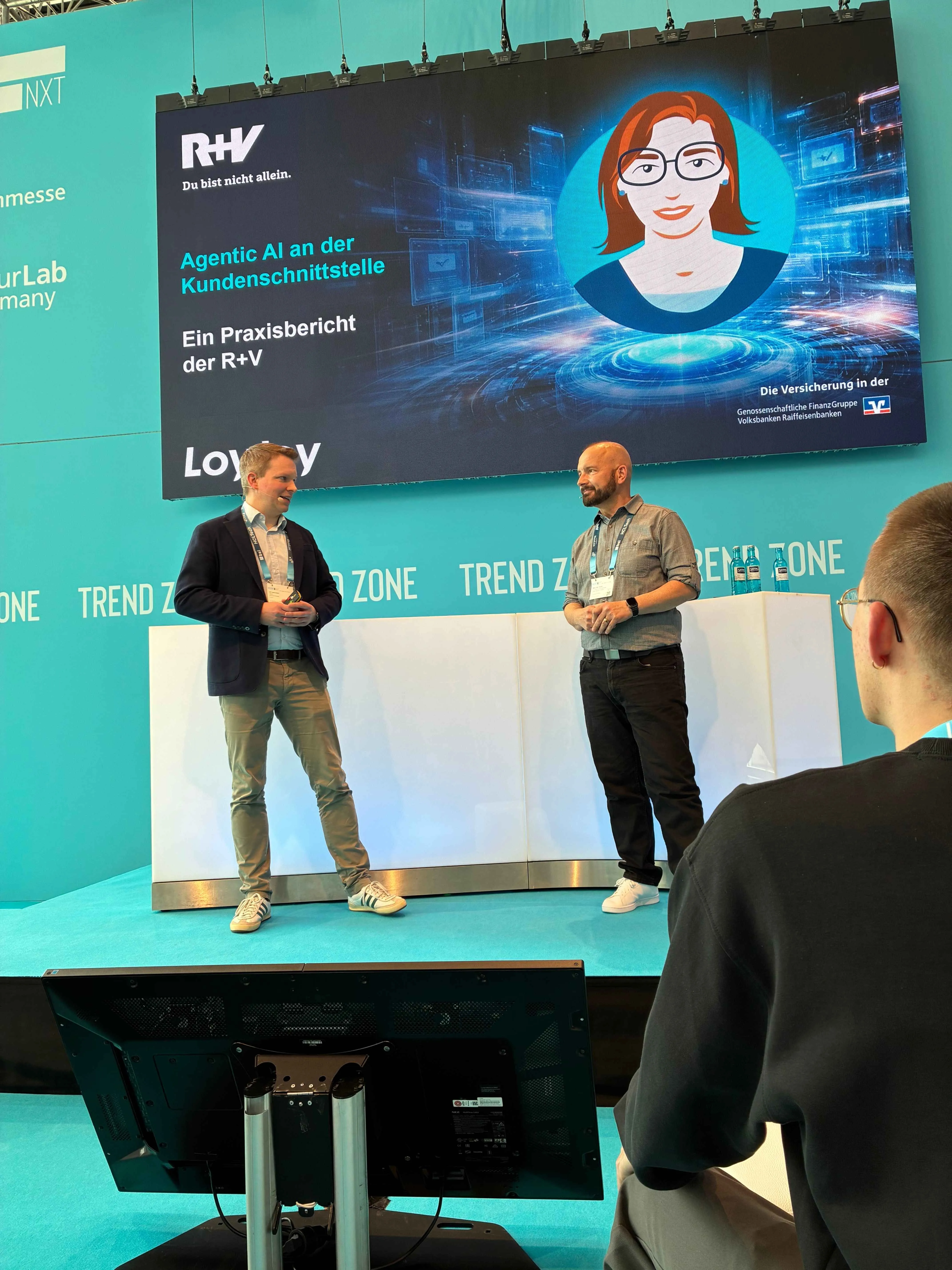 Ulf Loetschert von LoyJoy und Peter Paul Nasim von der R+V Versicherung beim gemeinsamen Vortrag zur KI-Assistenz Emmie auf der insureNXT 2026 in Köln.